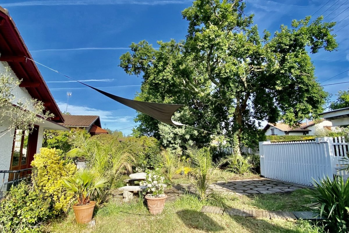 Jardin exposé sud avec table de jardin et voile d'ombrage