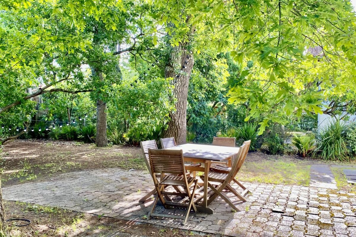 Table de jardin en teck dans l'espace ombragé sous les chênes